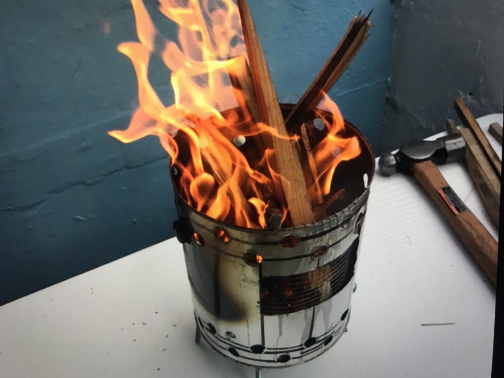 A paint can stove full of kindling the is in full blaze fire