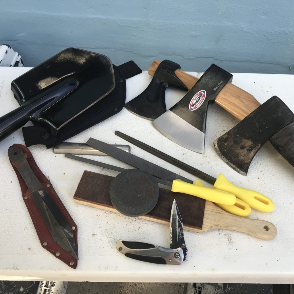 Collection of axes, knives on table.