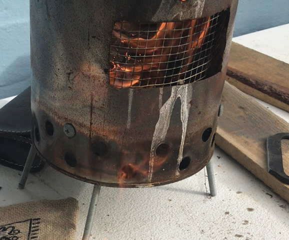 Fire inside a paint can stove. Flames seen through small opening in can