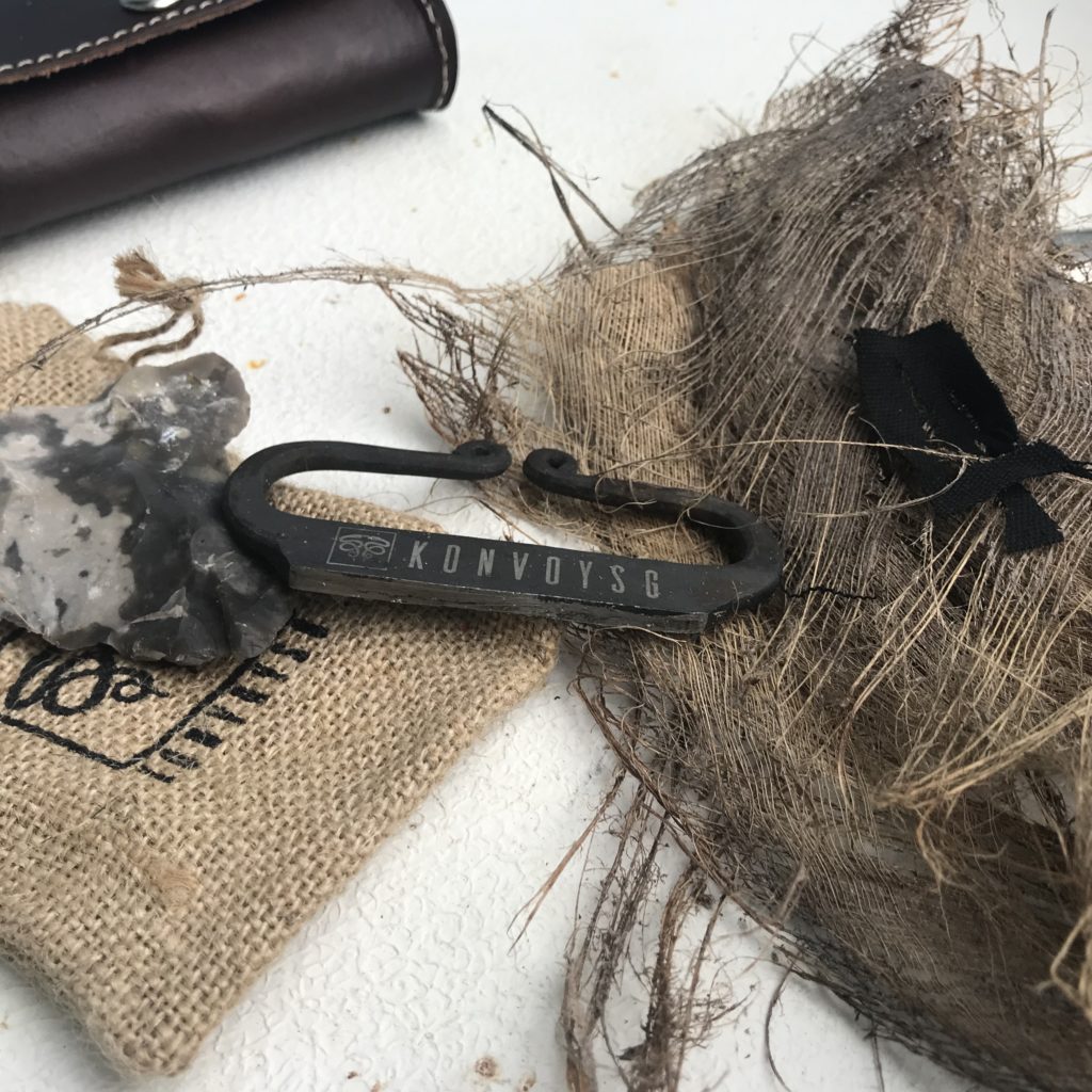 A iron hand stricter resting on a burlap bag and a tinder nest with a piece of char cloth