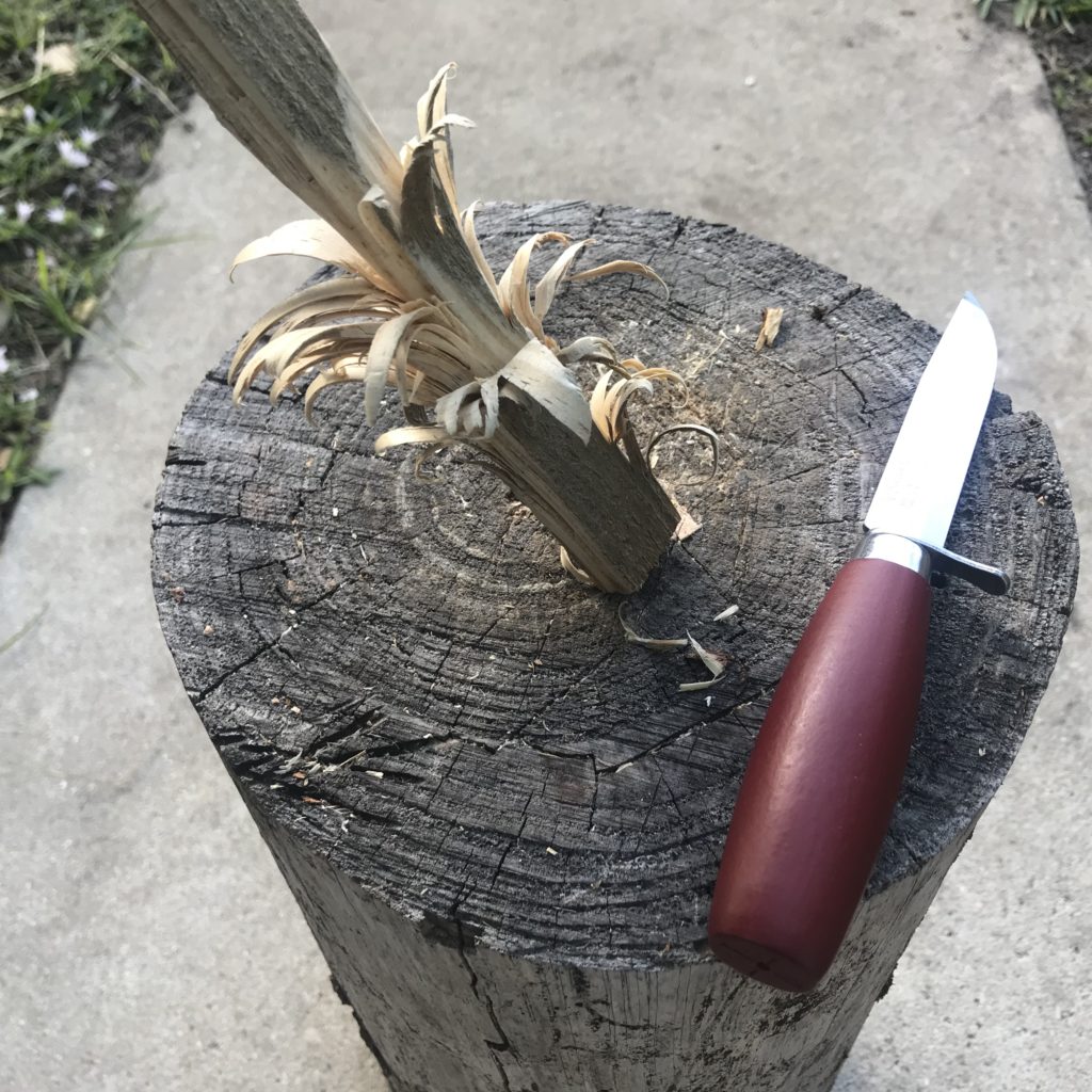 A feather stick and knife on a stump